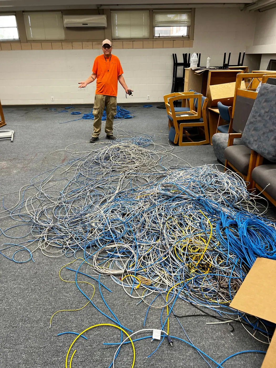 Technician standing beside a large pile of old cable pulled from a building