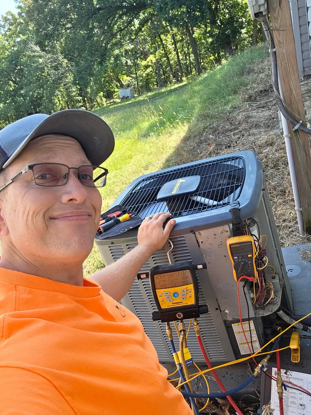 Technician testing an outdoor air conditioner with a digital manifold gauge