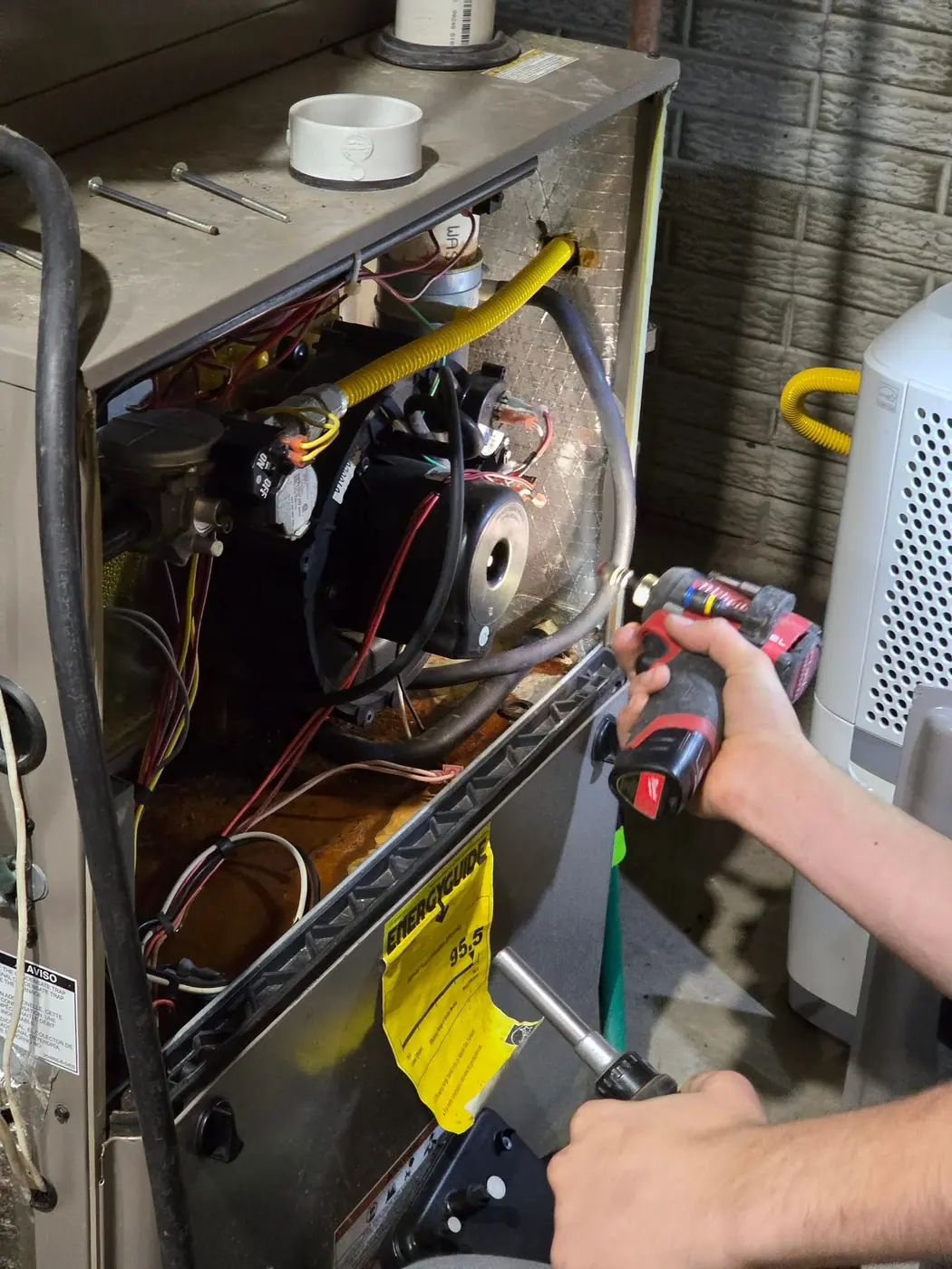 Technician wiring a new furnace with a cordless drill